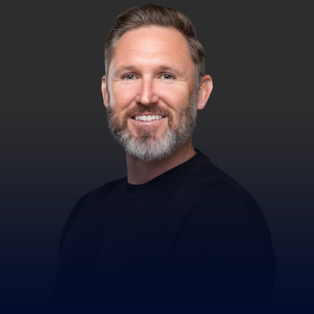 A man with gray hair and a beard smiling at the camera.