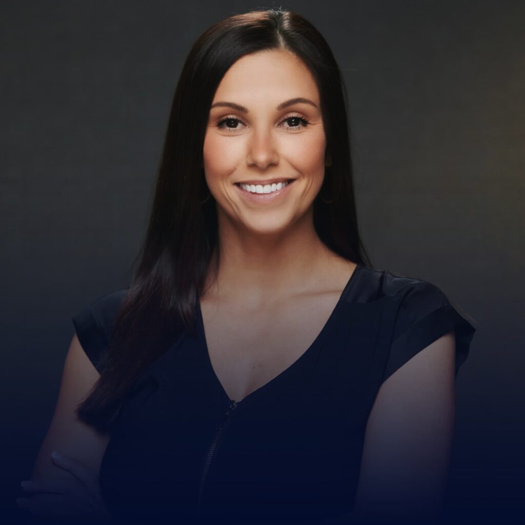 A smiling woman with long dark hair wearing a black top and jewelry